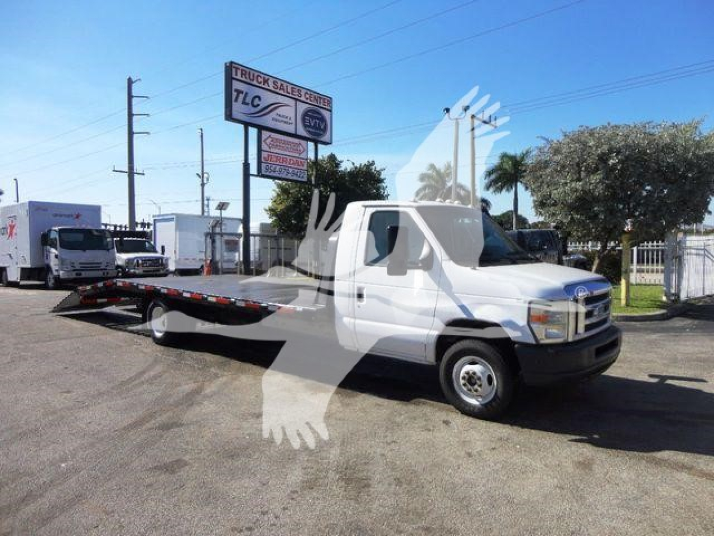 Ford E-450 flatbed tow truck in service view showing van truck cab and long flatbed