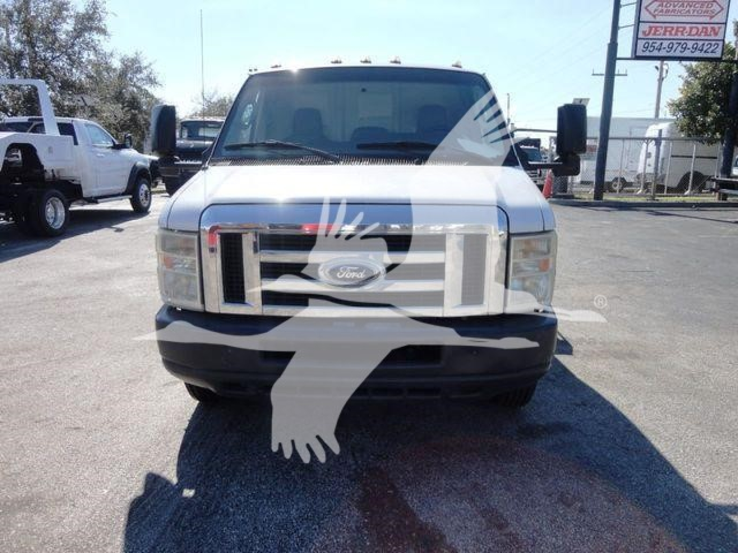Ford E-450 front view showing grille and bumper in a flatbed truck, with side mirrors and windshield visible.