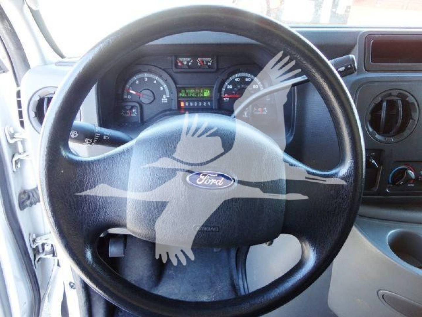 Steering wheel and dashboard of a 2011 Ford E450 van showing gauge cluster and controls.