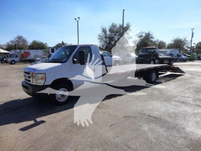 Flatbed tow truck from 2011 Ford E450 with white cab and black flatbed, side view showing extended bed and towing setup.