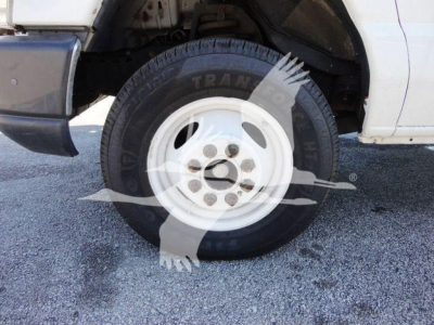 Truck front wheel and fender of a 2011 Ford E450 with a white wheel rim and black tire showing partial branding.