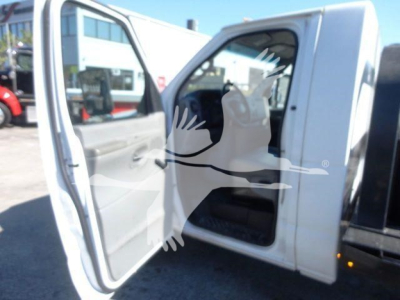 Ford E-450 cab interior and open driver-side door showing entry area and seat, white exterior, flatbed truck variant.