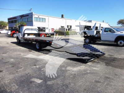 Flatbed tow truck in a parking lot showing a lowered ramp with black metal steps and a white cab, 2011 Ford E450 body style