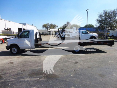 Flatbed tow truck in white with extended flatbed, side-view shows cab and wheel, Ford E-450 chassis in service.