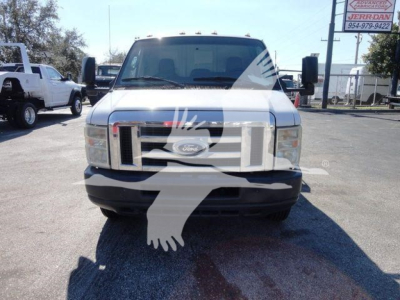 Ford E-450 front view showing grille and bumper in a flatbed truck, with side mirrors and windshield visible.