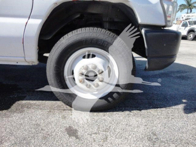 Ford E450 front wheel well and tire on a white flatbed truck showing wheel and fender.