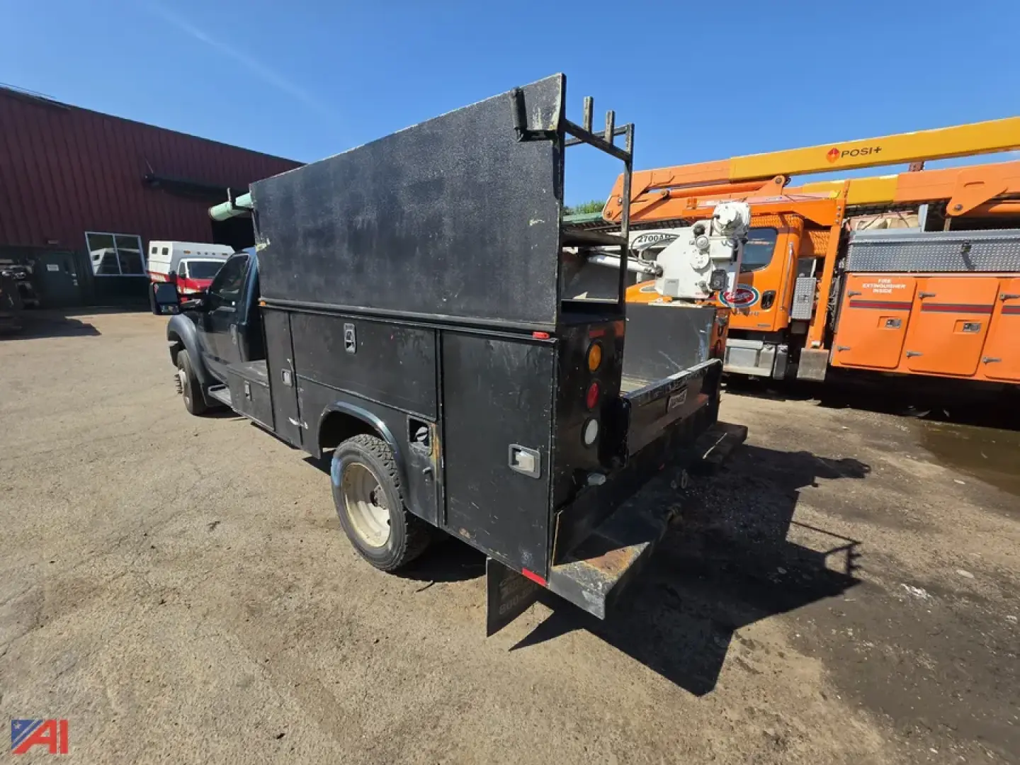 Ford F-550 utility truck rear/side view with toolbox and equipment rack in black, service body, single rear wheel, outdoors.