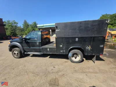 Ford F-550 utility truck side view with black utility box and ladder rack; single rear wheel; cab is dark; open cargo area.