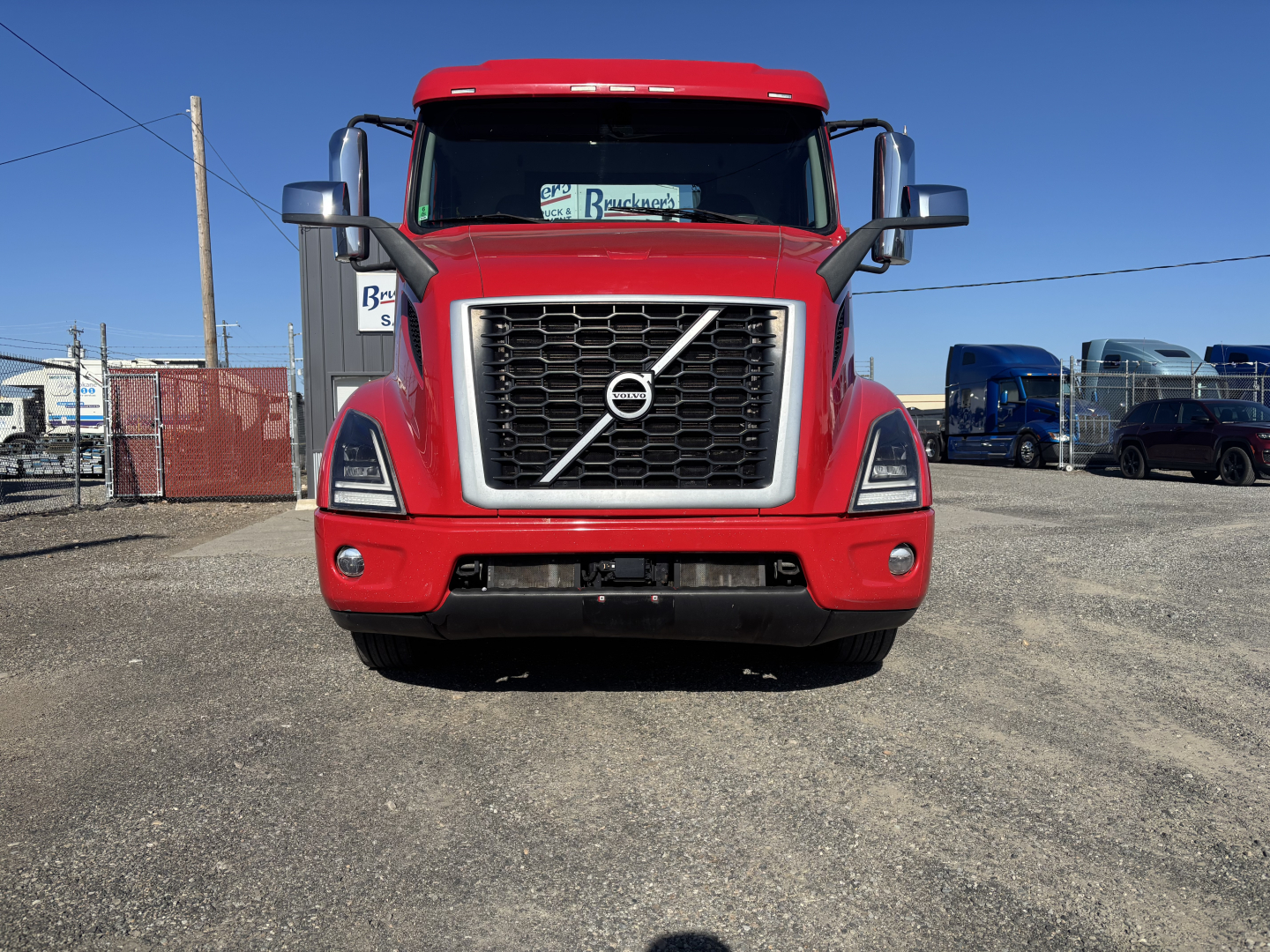 Volvo VNR64T300 truck front view showing Volvo grille and emblem, red cab, headlights, and bumper.