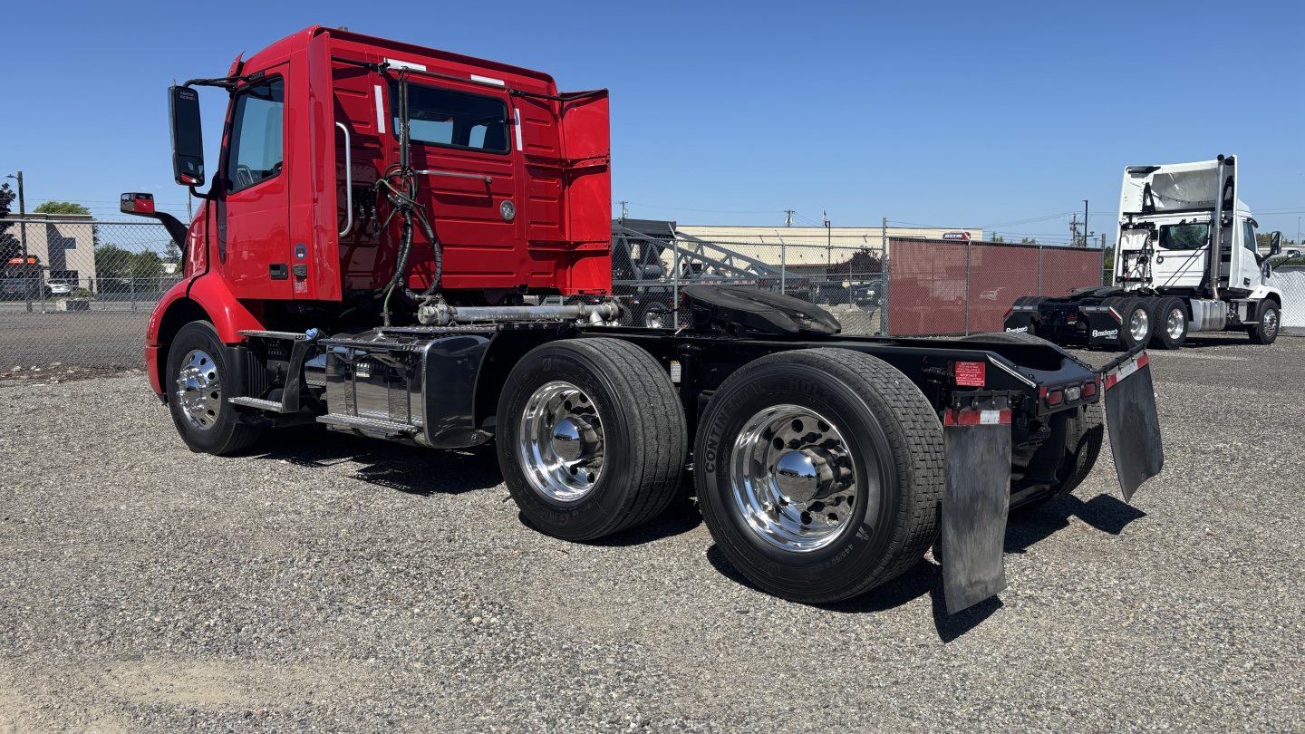 Volvo VNR64T300 truck chassis in red with exposed cab and dual rear axles, vacant fifth wheel area, chrome wheels, and fuel tanks visible.