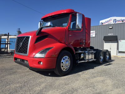 Volvo VNR64T300 conventional daycab tractor in red, front three-quarter view showing grille, cab, dual rear axles, chrome fuel tanks, and wheels.