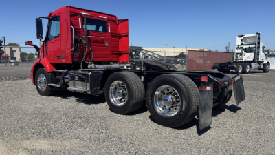Volvo VNR64T300 truck chassis in red with exposed cab and dual rear axles, vacant fifth wheel area, chrome wheels, and fuel tanks visible.