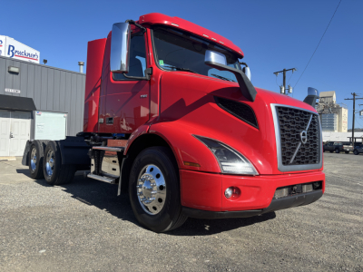 Volvo VNR64T300 truck in red, front three-quarter view showing grille, headlights, chrome mirrors, and dual rear axles.