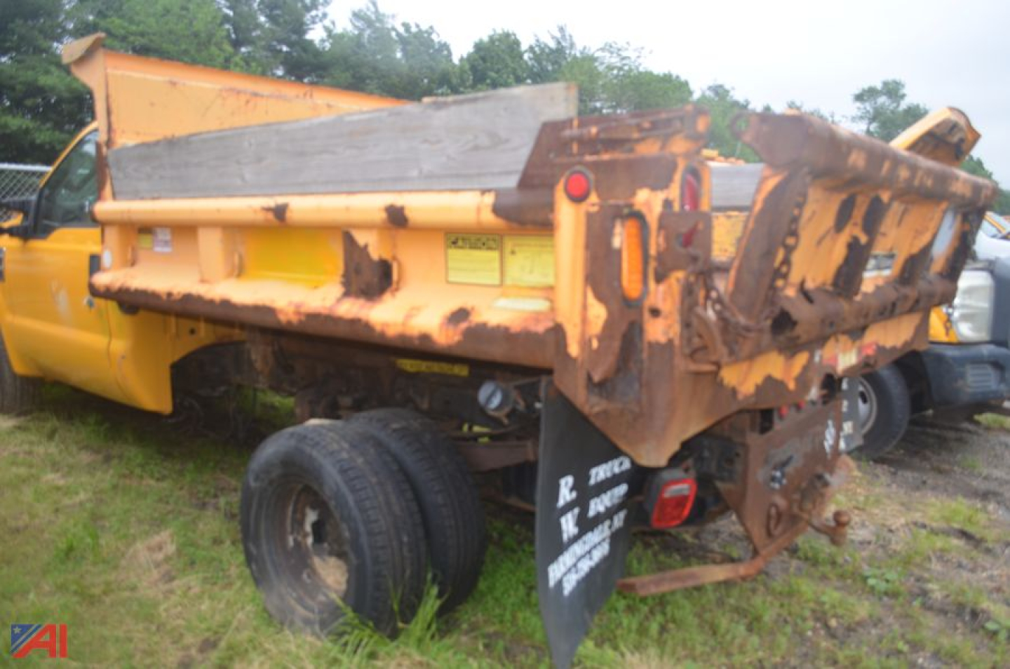 Dump truck bed of a 2010 Ford F350 Super Duty dump truck showing worn orange paint and metal bed with tailgate and support legs.