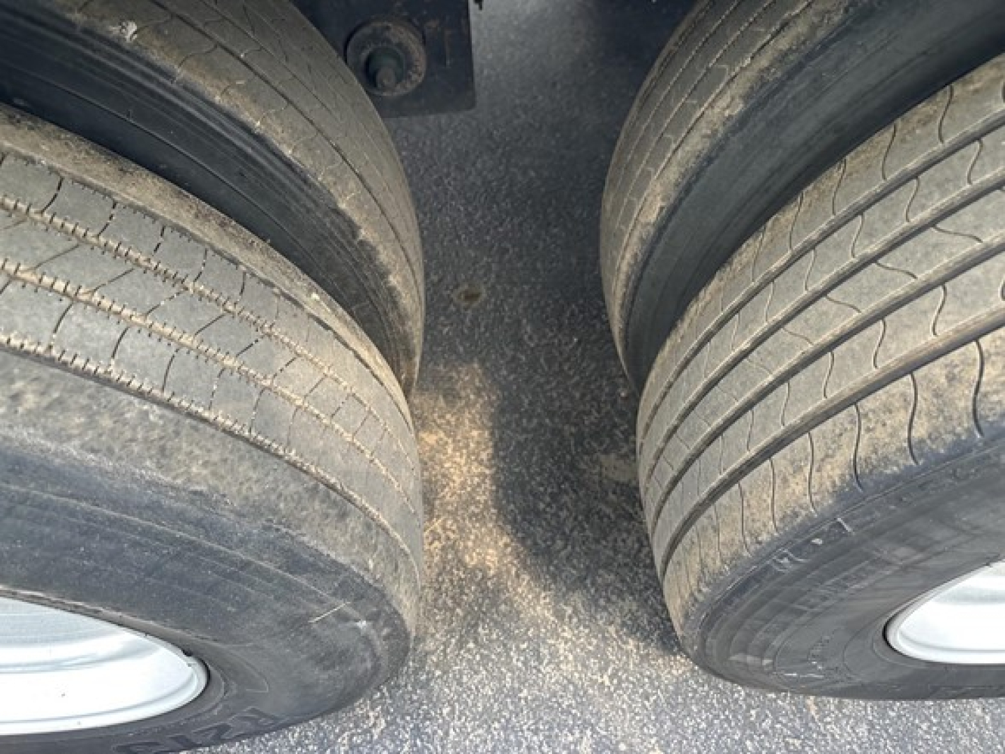 Dual rear trailer axles with tires visible in a top-down view showing worn tread and sidewalls.