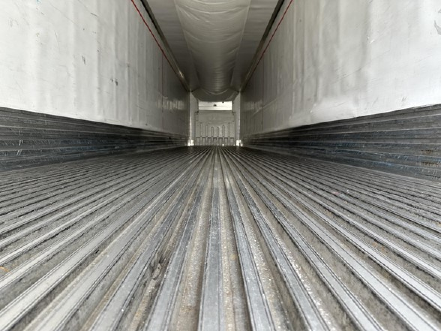 Trailer interior in empty cargo area of a 2015 Utility 3000R trailer showing corrugated metal floor and side walls with ribs, empty forward wall.