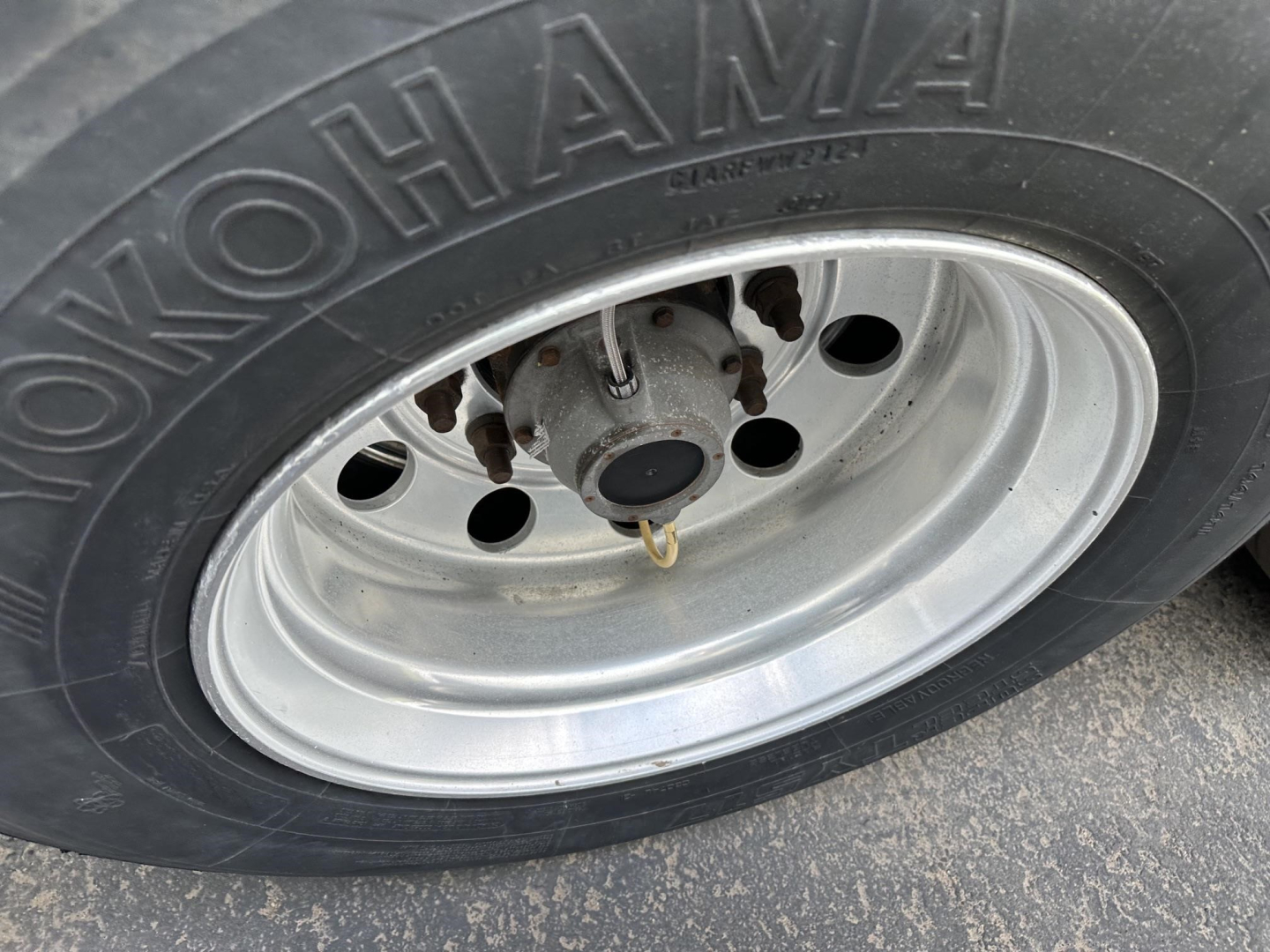 Trailer wheel close-up showing Goodyear tire and steel rim with hub and brake assembly visible; no text legible besides tire branding