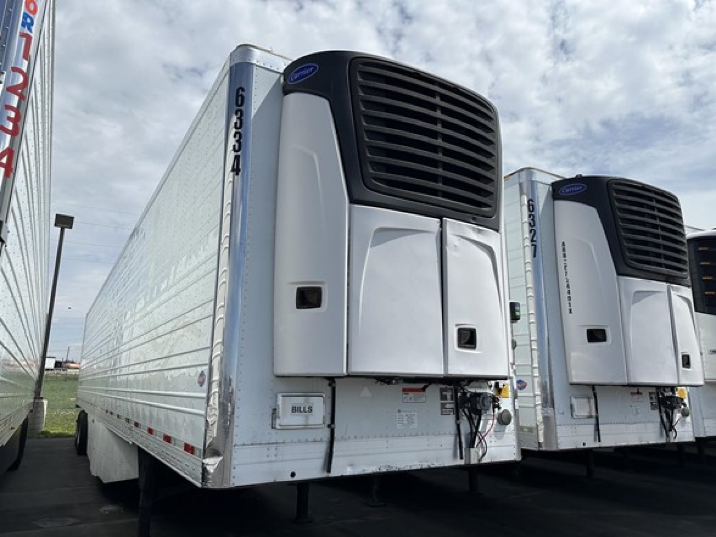 Utility refrigerated trailer 2015 model with front-mounted cooling unit, white body, reefer doors closed, corner details, VIN and stock markers along side, two other trailers visible.