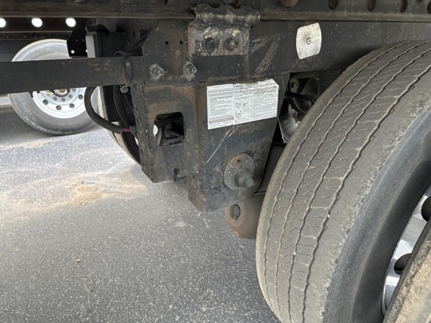 Rear undercarriage of a 2015 Utility 3000R trailer showing suspension brackets, frame, and wheel with a small identification plate on a rust-colored chassis.