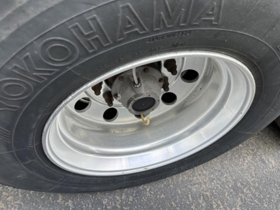 Trailer wheel close-up showing Nokohama tire and polished steel wheel with lug nuts.