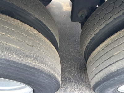 Dual rear trailer tires in contact with road surface under a Utility 3000R trailer, showing worn tread and wheel hubs.