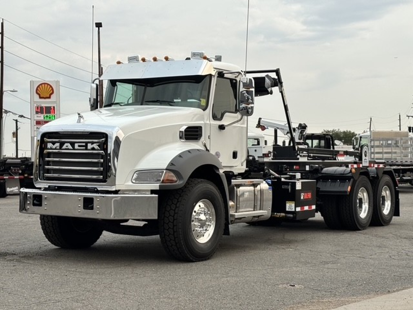 Mack GR64B truck in a dealership lot showing front grille with MACk letters and heavy-duty chassis, no cab interior visible.