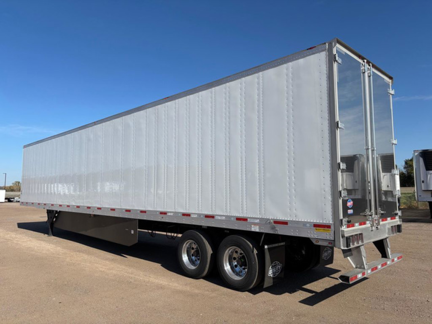 Utility Dx dry van trailer showing exterior side and rear doors with tri-axle configuration and reflective markings.