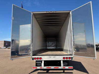 Trailer rear view with open doors showing empty inside cargo space; chrome reflective exterior, LED taillights, and wooden floor.