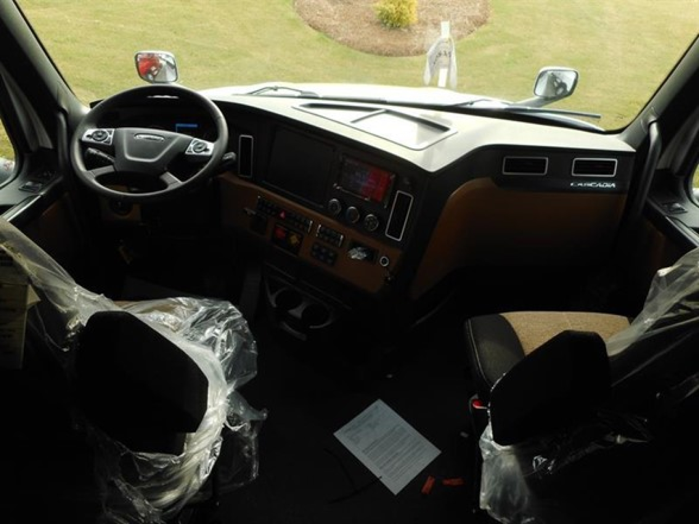 Freightliner Cascadia 126 truck interior view showing steering wheel, dashboard, and center console with controls.