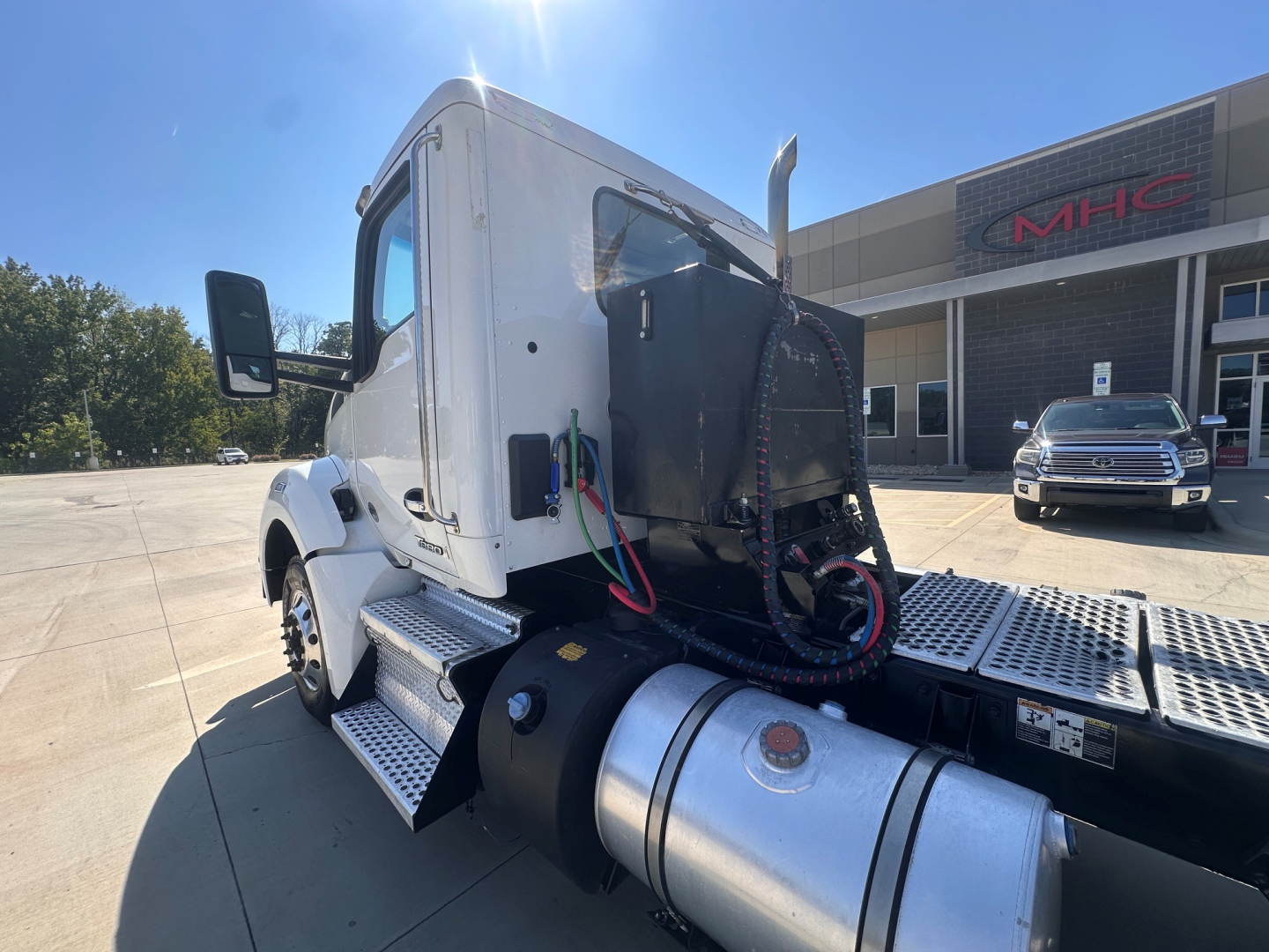 Kenworth T880 cab and chassis side view showing fuel tank and catwalk with hose connections near cab; no visible labels legible on image.