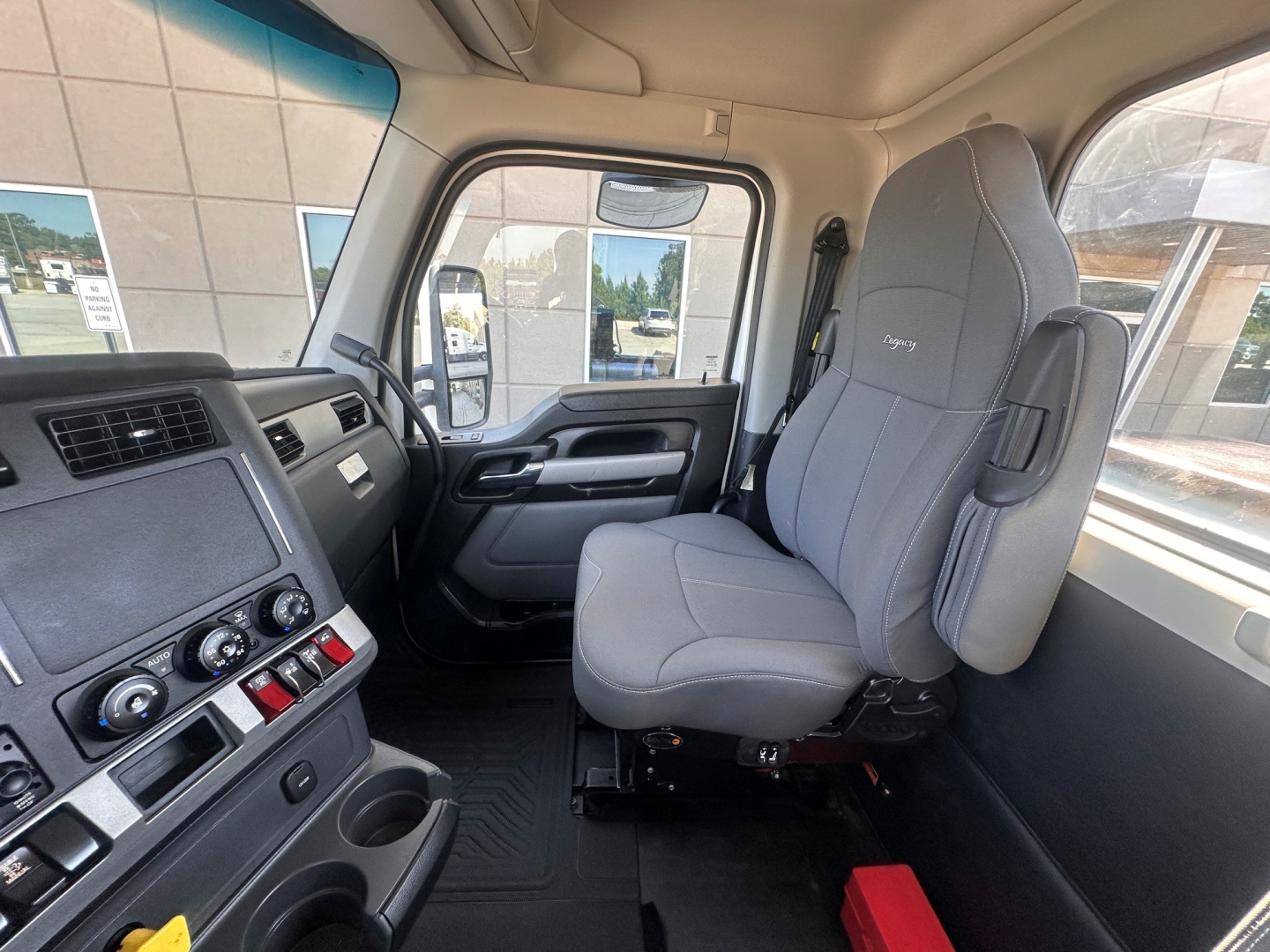 Kenworth T880 cab interior showing gray driver seat and dashboard with controls, steering wheel, and door,”