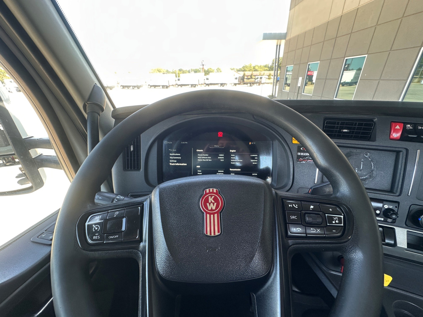 Kenworth T880 interior view of steering wheel and dashboard, with brand emblem on wheel and digital gauges visible.