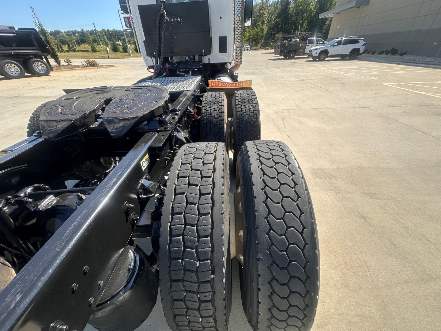 Truck chassis showing two rear dual tires and fifth wheel area of a 2022 Kenworth T880, view from behind cab in an open lot.