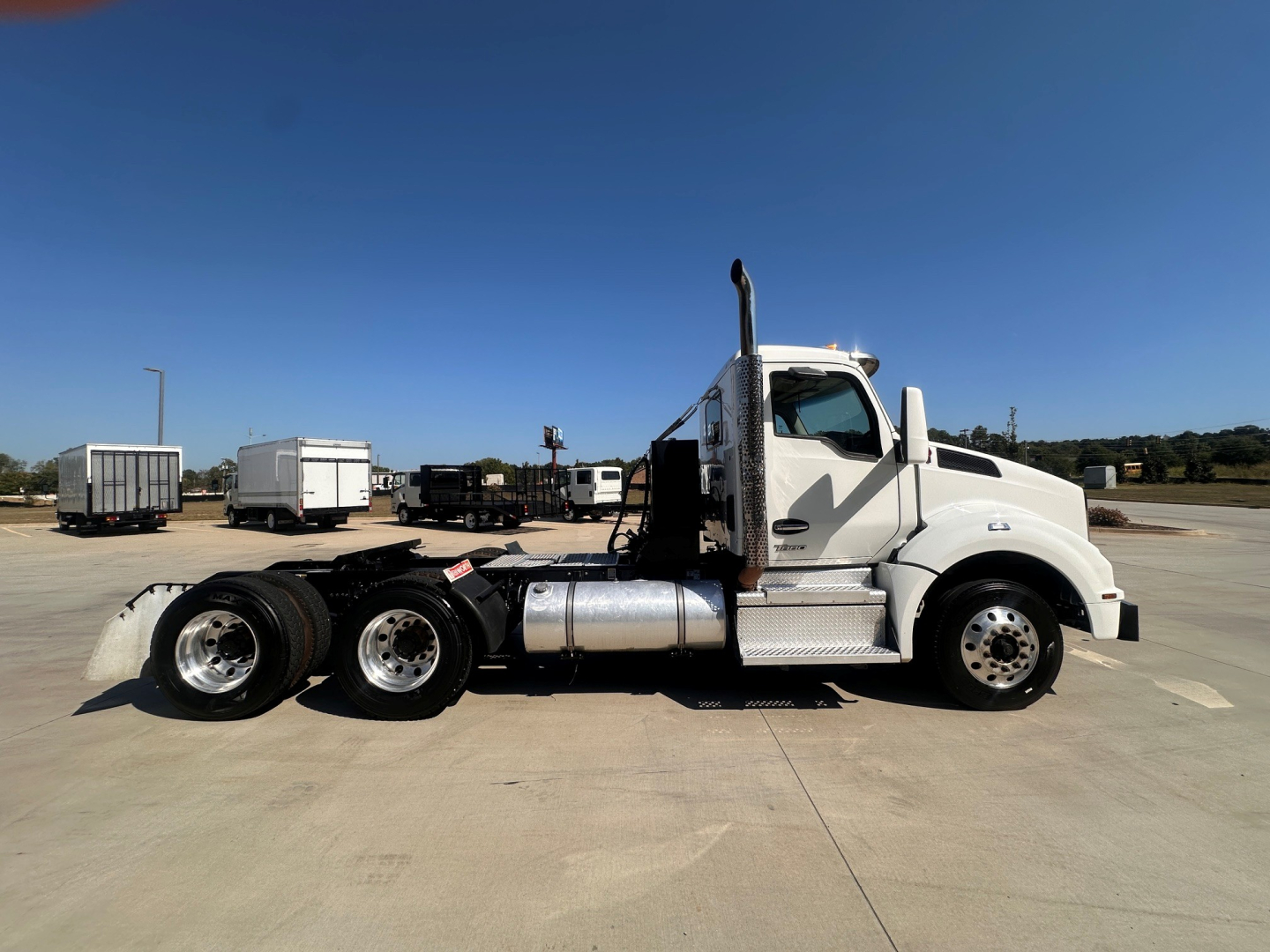 Kenworth T880 conventional daycab tractor side view showing cab, fuel tanks, rear dual axles, and chrome exhaust stack.