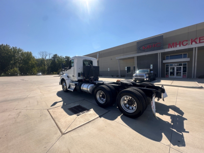 Kenworth T880 conventional daycab tractor chassis and cab in a parking lot showing rear trailer hitch and dual rear axles.