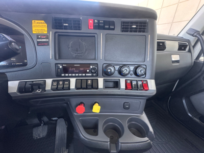 Kenworth T880 dash and center console showing gauges, switches, and cup holders; yellow and red latches; VIN and stock details not visible in this frame.