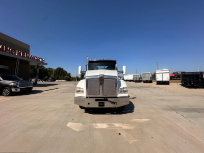 Kenworth T880 front view in a parking lot with grille, large bumper, and side mirrors.