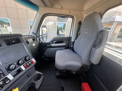 Kenworth T880 cab interior showing gray driver seat and dashboard with controls, steering wheel, and door,”