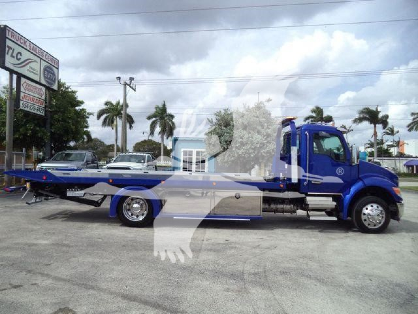 Kenworth T280 rollback tow truck side view showing blue cab and flatbed.