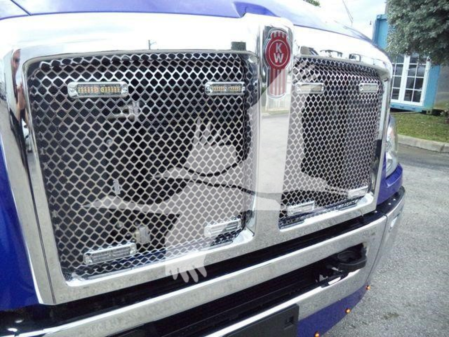 Kenworth T680 style front grill with chrome mesh, KW emblem and two side badge plates visible.