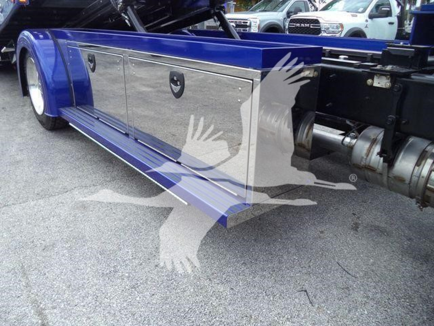 Truck bed side compartments on a blue 2025 Kenworth T280 rollback truck showing chrome storage boxes and towing hitch area.