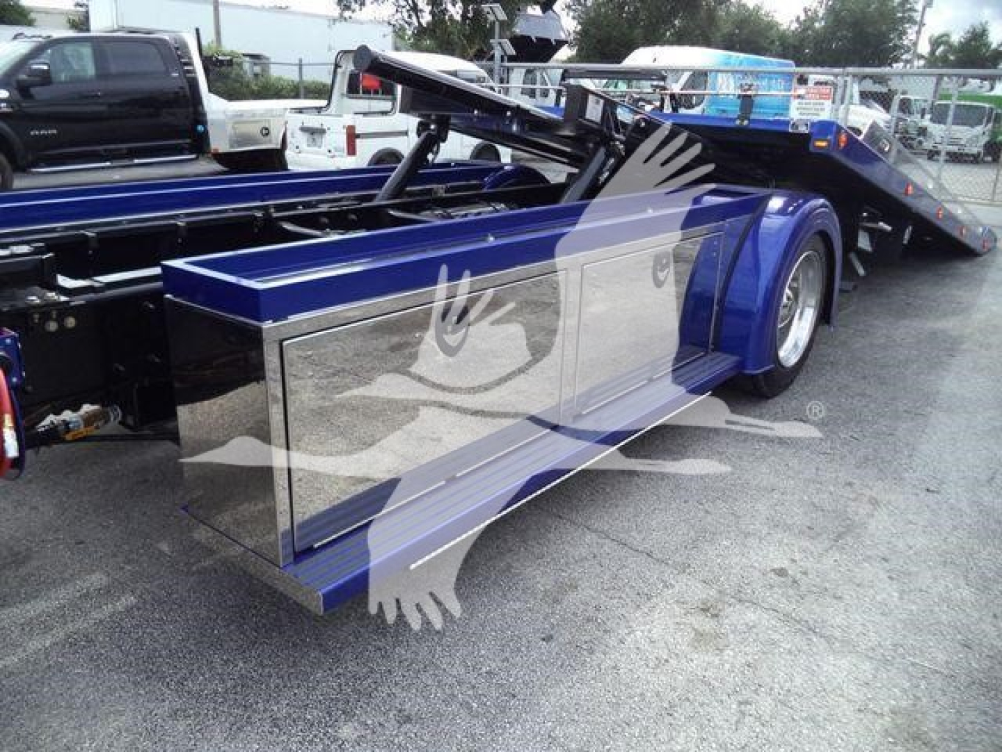 Kenworth T280 rollback with chrome side toolbox and blue paint, rear hydraulic tilt bed visible.