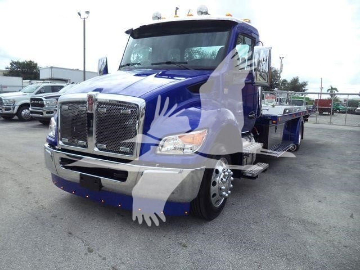Kenworth T280 rollback tow truck front view with blue cab and chrome grille. Side steps visible and front bumper.