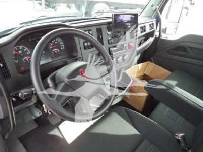Kenworth T280 cab interior showing steering wheel dashboard and center console with a cardboard box on the passenger seat.