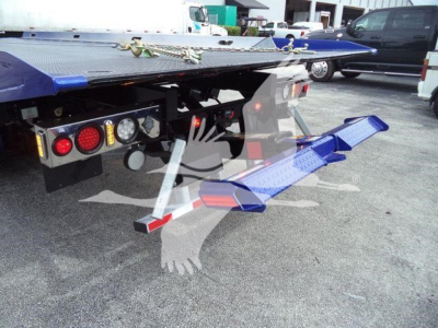 Rear view of a 2025 Kenworth T280 rollback bed showing wheel-lift arms and hydraulic controls with reflective lights.