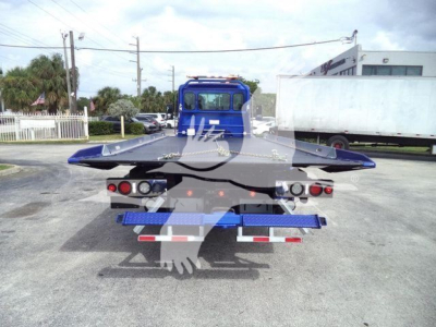 Kenworth T280 rollback bed viewed from rear; blue truck with flatbed platform, multiple lights, and reflective safety markings.