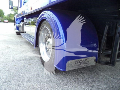 Truck side view showing front fender and wheel of a blue Kenworth T-series rollback truck with TLC mudguard plate.