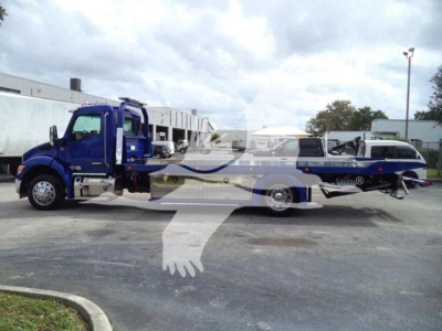 Truck with a rolled—back tow bed, blue chassis, and a flatbed tilt; side view shows Kenworth T280 style cab; no legible brand text visible in image