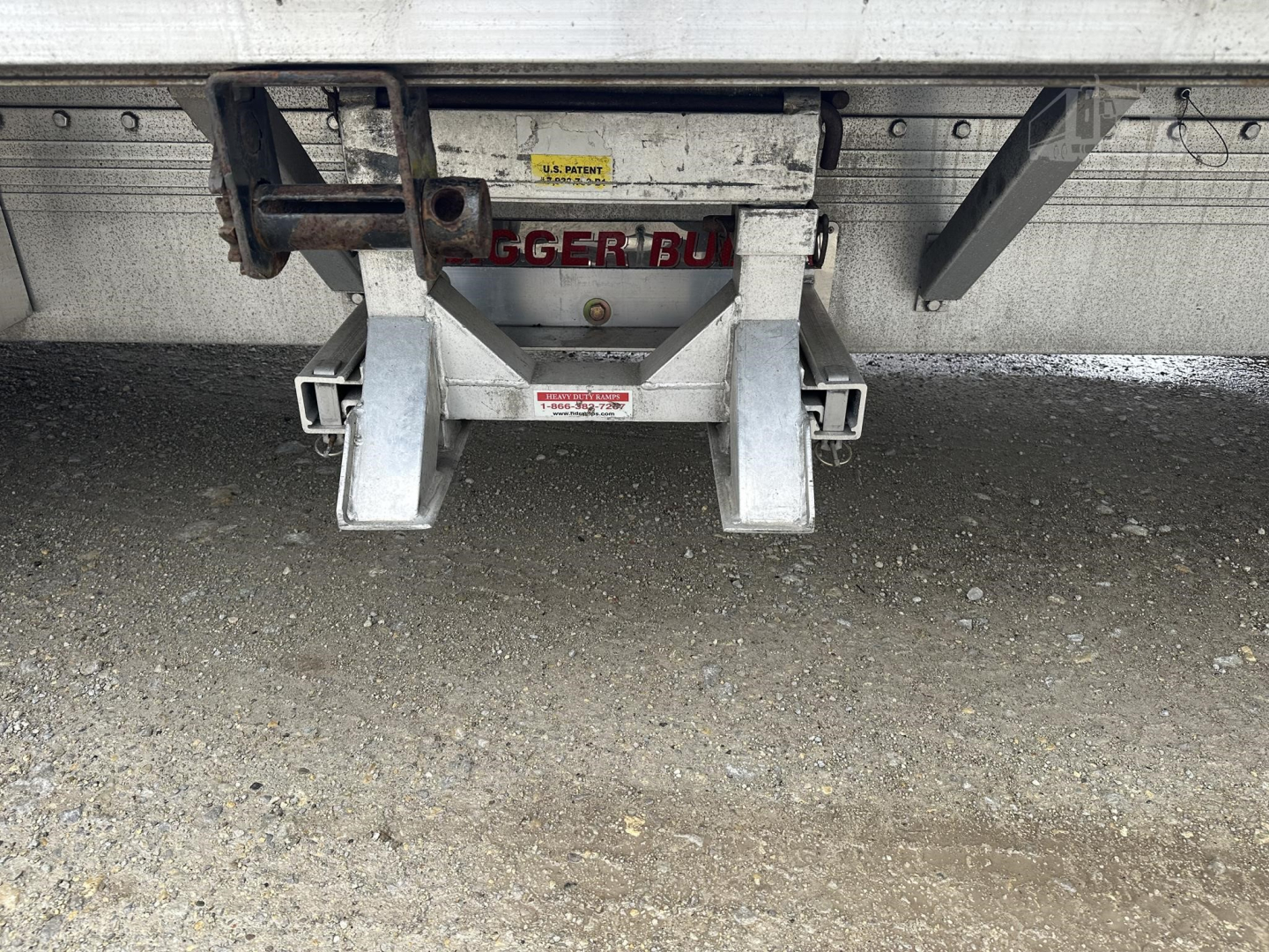 Rear view of a used 2019 Reitnouer Big Bubba drop deck trailer hitch assembly with warning labels and a central latch.