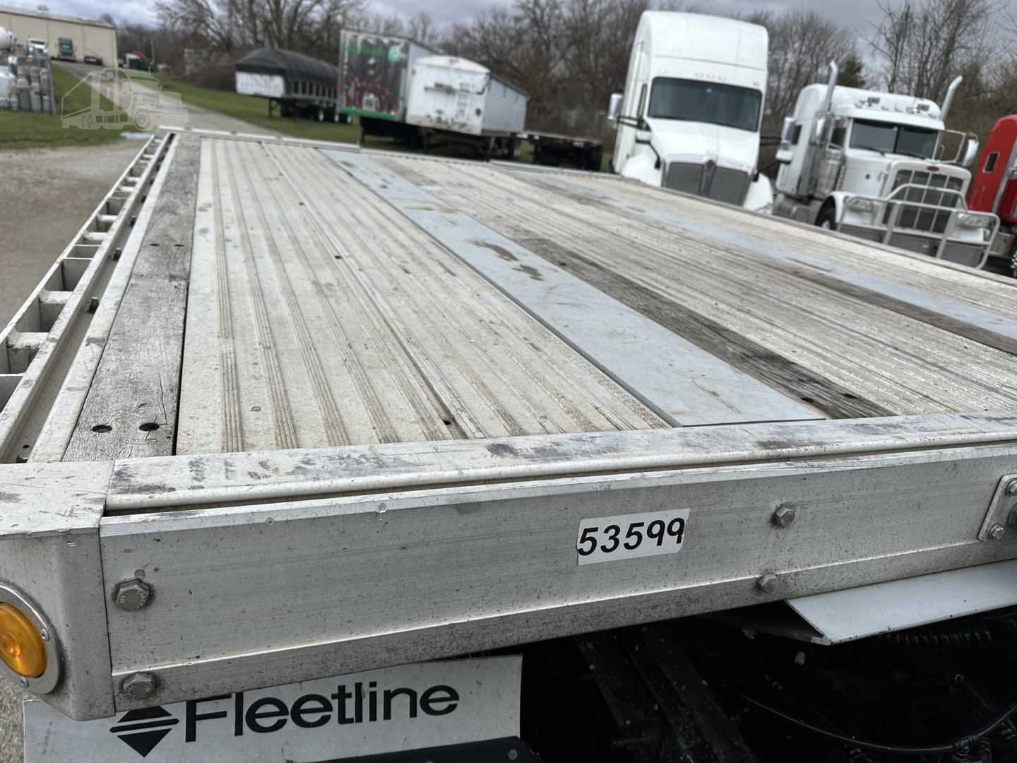 Flatbed trailer deck showing metal planks and side rail with Fleetline logo and inventory number 53599.